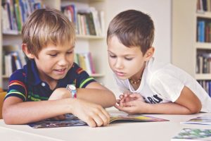 Two elementary school age boys reading a magazine